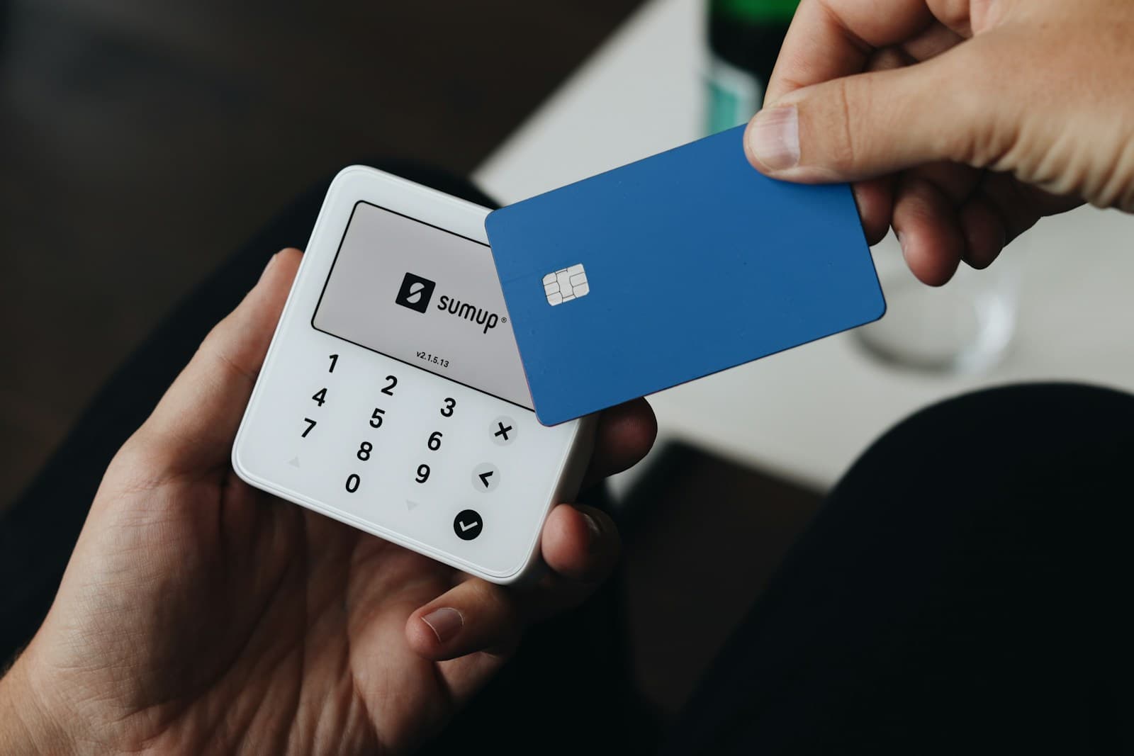 Hands holding a blue chip card and a portable card terminal.